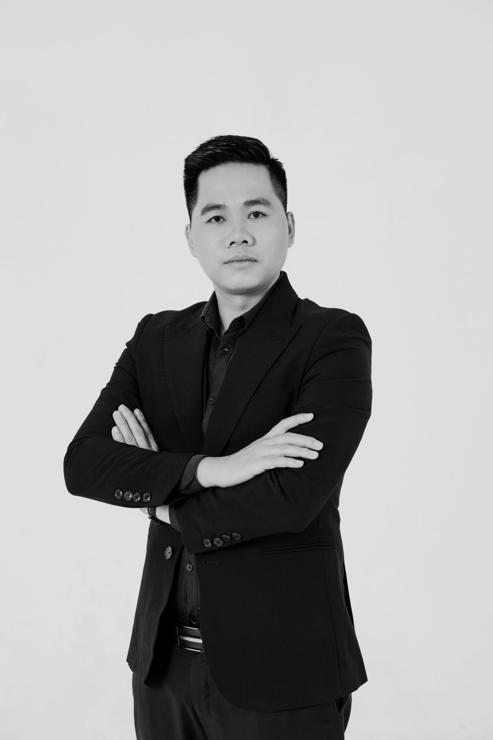 Elegant portrait of an Asian man in formal attire with arms crossed, photographed in studio.