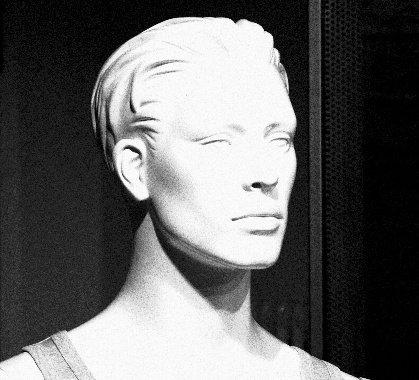 Close-up of a monochrome mannequin head with dramatic lighting and shadows.