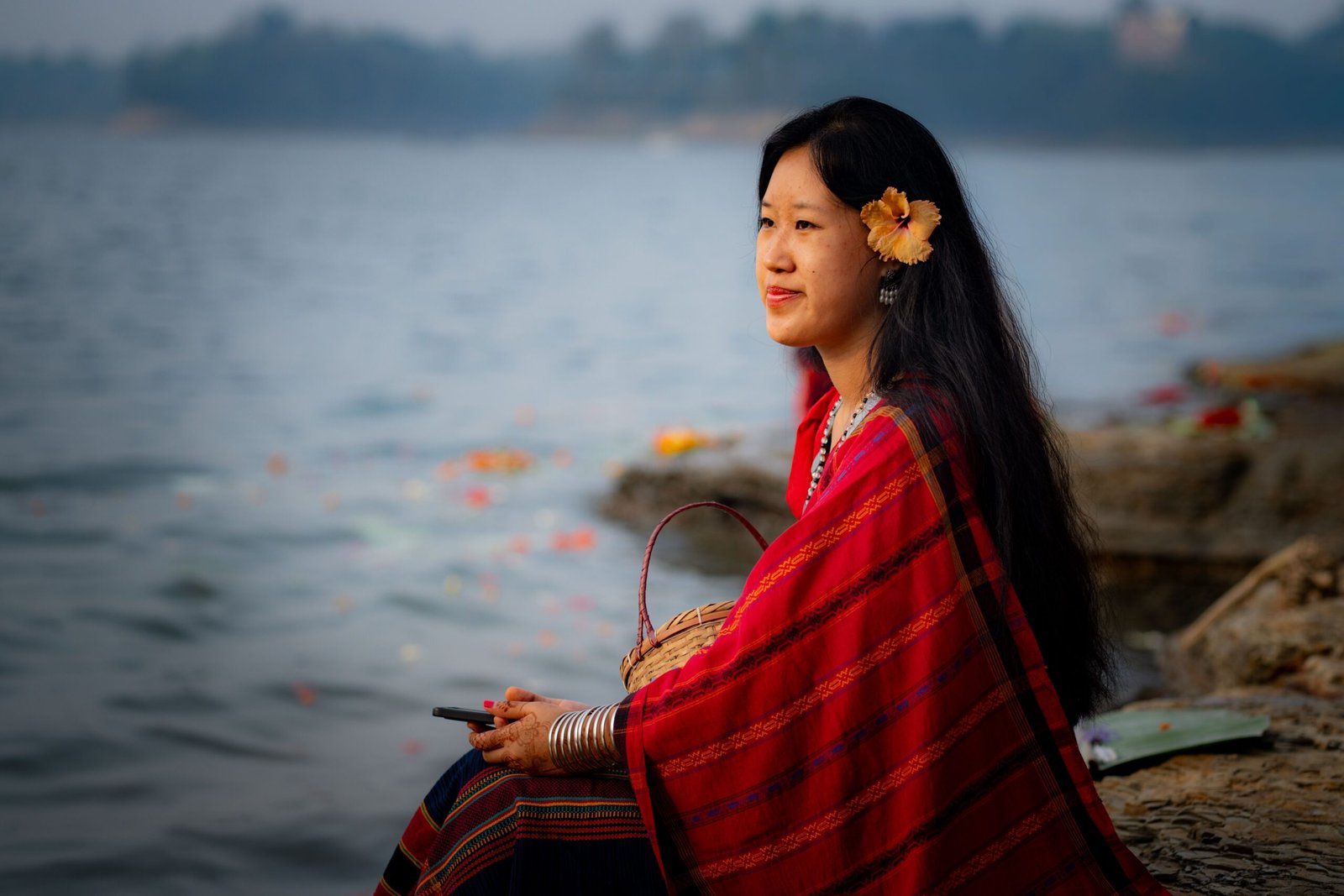 Woman in traditional dress sits by Lake Kaptai in Rangamati, Bangladesh, enjoying a serene moment.